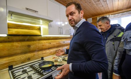 Мужчина у газовой плиты жарит яичницу
