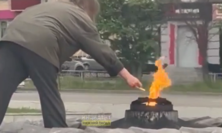 Женщина в Нижнем Тагиле прикуривает сигарету от Вечного огня.
