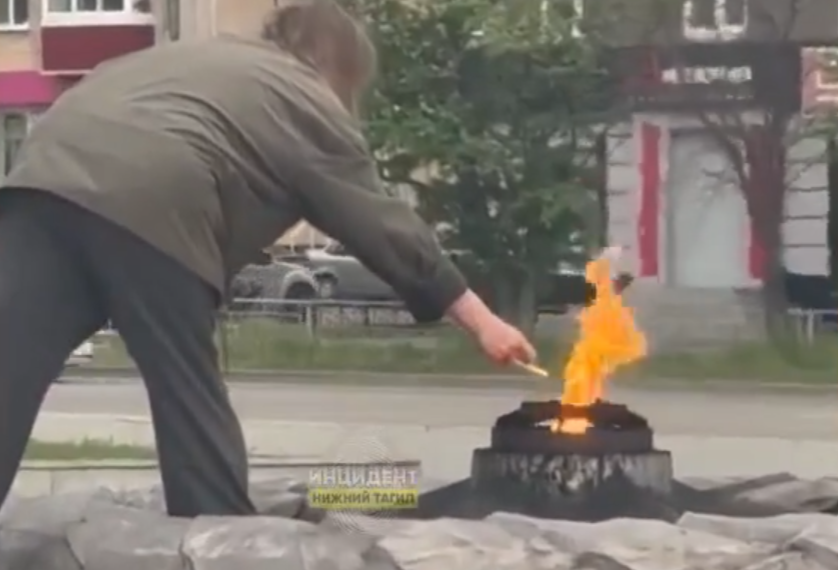 Женщина в Нижнем Тагиле прикуривает сигарету от Вечного огня.