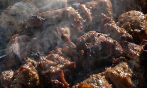 Аппетитное мясо на шампурах, жарящееся на углях в мангале на уральской даче.