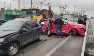 Разбитые легковые автомобили и грузовик на перекрестке в жилом районе города после массовой аварии.