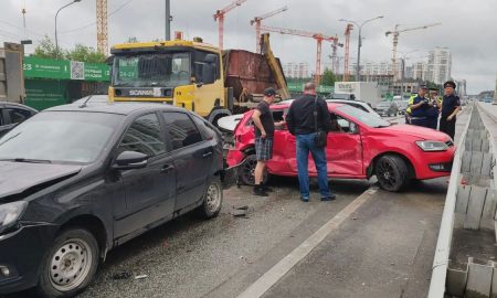 Разбитые легковые автомобили и грузовик на перекрестке в жилом районе города после массовой аварии.
