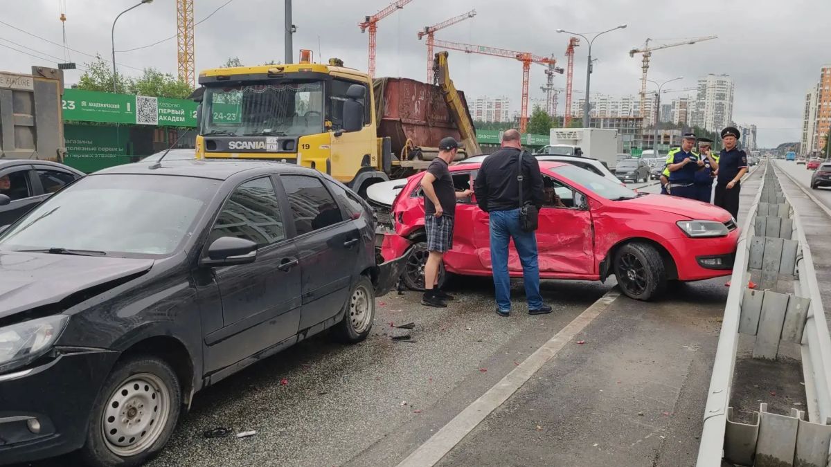 Разбитые легковые автомобили и грузовик на перекрестке в жилом районе города после массовой аварии.