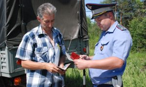 Инспектор ДПС проверяет документы у автовладельца.