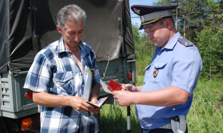 Инспектор ДПС проверяет документы у автовладельца.
