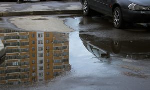 Жилой дом отражается в луже.