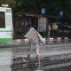 Женщина, накрытая платком, пытается спастить от ливня.