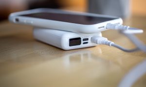 Смартфон заряжается от небольшого белого внешнего аккумулятора