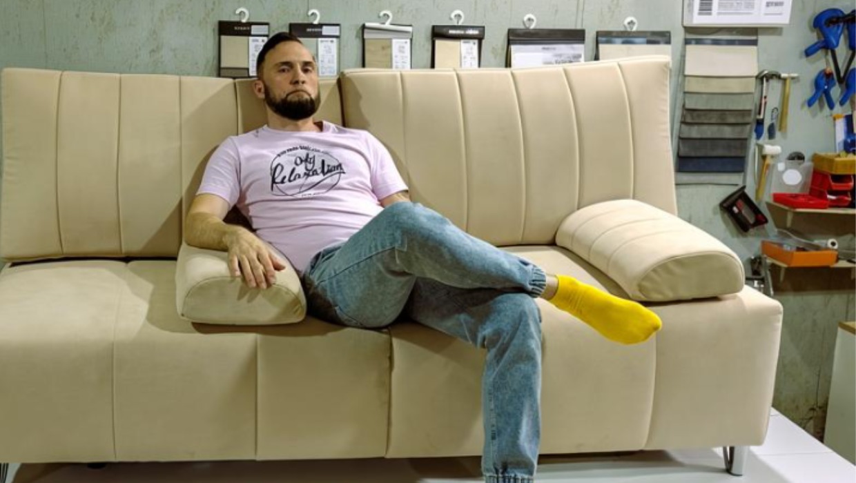 Мужчина сидит на чистом диване.